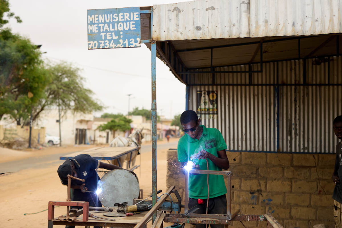 Ameth et Moussa sont deux équipementiers. Ils travaillent à la fabrication d’un torréfacteur d’arachide pour la PME Kadior. Travail en atelier / achat de pièces chez le quincailler / maintenance de l’équipement chez Kadior / test sur la plateforme Biomasse Energie de Biostar.